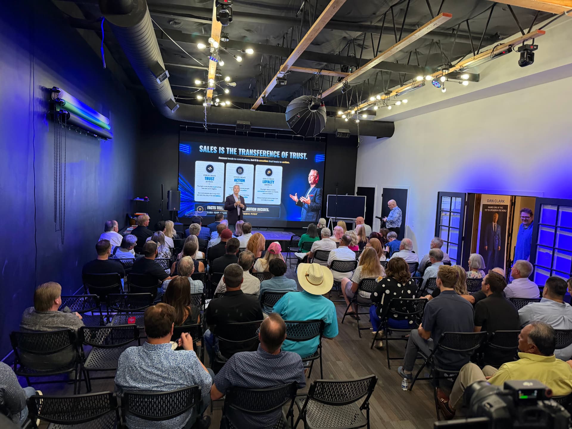 Blue-lit studio during a live presentation with rows of seating